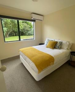 een slaapkamer met een bed met een groot raam bij Gordonton Greenmeadows Cottage in Taupiri