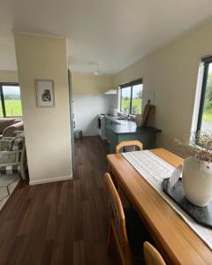 een keuken en een woonkamer met een houten tafel en een eetkamer bij Gordonton Greenmeadows Cottage in Taupiri