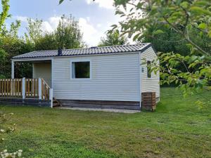 a small white shed with a deck in a yard at Mobil-home cosy avec terrasse à Loudéac - API-1-52-1116 in Loudéac
