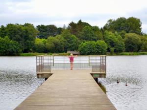 a person standing on a pier over a lake at Mobil-home cosy avec terrasse à Loudéac - API-1-52-1116 in Loudéac +1 photo