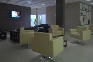 a waiting room with yellow chairs and a flat screen tv at Skala Traveling Hotel in Cuiabá