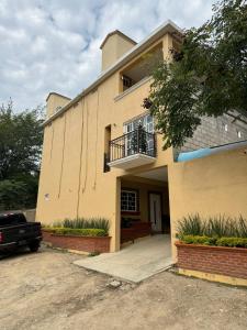 Una gran casa amarilla con balcón y entrada para coches. en Departamentos El Olvido, en Jalpan