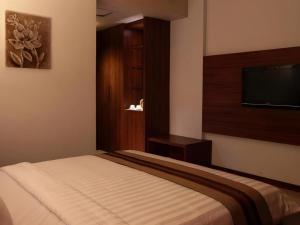 a bedroom with a bed and a flat screen tv at Mega Permata Hotel in Padangsidimpuan