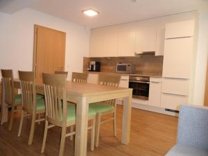 Il comprend une cuisine et une salle à manger avec une table et des chaises en bois. dans l'établissement Ferienwohnung Sonnalpen, à Damüls