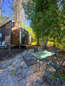 Una mesa y sillas frente a una pequeña casa. en Hill Creek Tiny House 5 by Tiny Away, en Perwillowen
