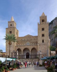 a church with two towers and people walking in front of it at Lo duca luxury home in Cefalù