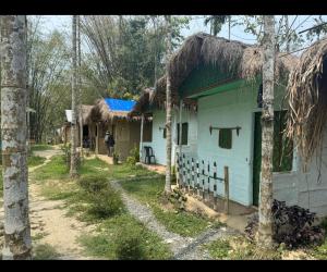 a house with a thatched roof in a forest at Tranquil Bambusic Bliss in Kāziranga