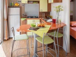 a kitchen with a table and chairs and a refrigerator at Mobil-home avec Terrasse, 3 Chambres, 4 Personnes - API-1-52-1131 in Saint-Rome-de-Tarn
