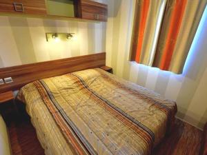 a bedroom with a bed with a wooden headboard and a window at Mobil-home avec Terrasse, 3 Chambres, 4 Personnes - API-1-52-1131 in Saint-Rome-de-Tarn +14 photos