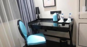 a desk in a hotel room with a blue chair at Xana Hotelle Neijiang City Center Branch in Neijiang