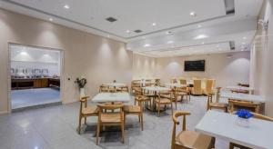 a dining room with tables and chairs and a tv at Yitel Shanghai Hongqiao Railway Station National Convention and Exhibition Center in Fangjiayao