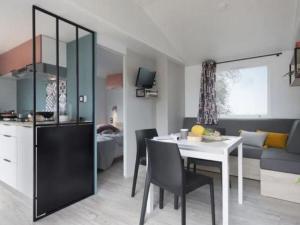 a kitchen and living room with a table and a dining room at Mobil home 32m² avec terrasse au Camping De La Cascade, 3 chambres pour 6 personnes - API-1-52-1162 in Saint-Rome-de-Tarn