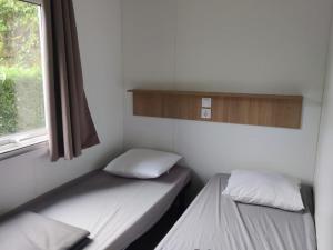 Mobil Home avec Terrasse - 4 personnes - API-1-52-1165 في Saint-Rome-de-Tarn: سريرين في غرفة صغيرة بها نافذة