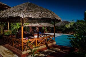 a restaurant with a straw umbrella next to a swimming pool at Edena Kely in Mahajanga