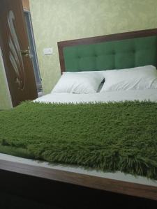 a bed with a green blanket on top of it at Зелений Рай in Dilijan