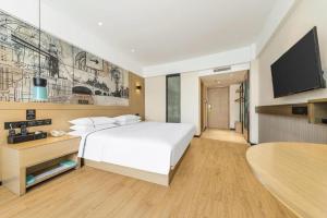 Schlafzimmer mit einem weißen Bett und einem Flachbild-TV in der Unterkunft City Comfort Inn Lingshui Central Avenue Bus Station in Lingshui