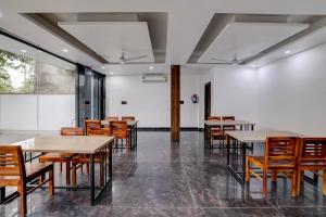 FabHotel Groom Room في نويدا: غرفة طعام بها طاولات وكراسي وجدار أبيض +23 صورة