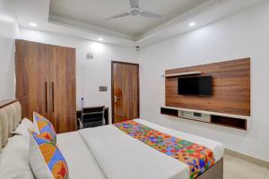 FabHotel Groom Room في نويدا: غرفة نوم مع سرير وتلفزيون بشاشة مسطحة