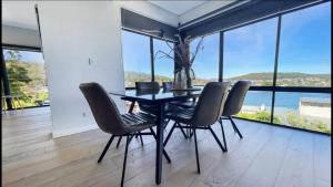 Bella Vista - Coastal Waterviews في Empire Bay: غرفة طعام مع طاولة وكراسي سوداء