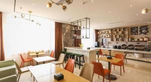 ein Restaurant mit Tischen und Stühlen und einer Küche in der Unterkunft City Comfort Inn Chengdu Wenjiang Zhujiang Square Guanghua Park Metro Station in Chengdu