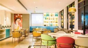 un ristorante con sedie e tavoli colorati di Magnotel Hotel Huangshan Scenic Area Transfer Center a Mount Huangshan