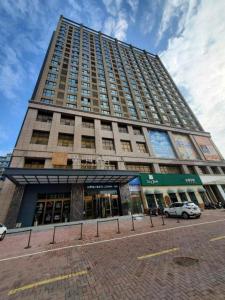 a tall building with a car parked in front of it at James Joyce Coffetel Xinyang Municipal Government Railway Station in Xinyangzhou Zhan