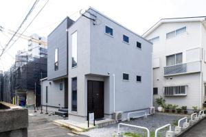 a white building with a door in a yard at Amp Flat 清川 in Sumiyoshi