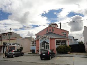 un edificio rosa con coches estacionados frente a él en Hotel Sehuen en Río Gallegos