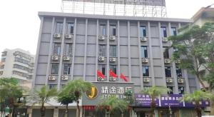 湛江JTOUR Inn Zhanjiang Poly Yuandian Plaza的一座灰色的大楼，前面插着红旗