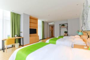 una camera d'albergo con due letti e una TV a schermo piatto di Vatica Hotel Hefei Yaohai Longgang Subway Station a Hefei