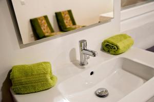 a bathroom sink with a green towel and a mirror at Marco Polo Party Hostel in St. Julianʼs