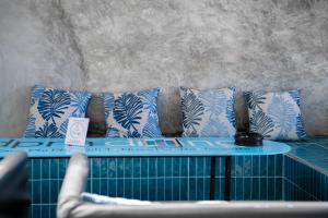 a couch with blue and white pillows on it at DPM Koh Tao Diving Hotel & Bar in Ko Tao