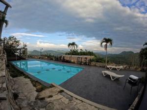 a swimming pool with a bench and palm trees at Hotel Monte Ixk'al Xilitla in Xilitla