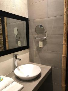 Un baño con un lavabo blanco y un espejo. en Hotel Monte Ixk'al Xilitla, en Xilitla