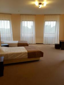 a hotel room with two beds and two windows at Hotel Kremlevsky in Ryazan