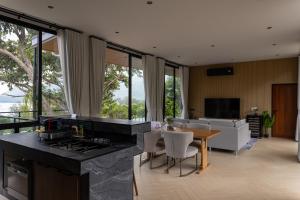 a kitchen with a table and a living room at Escape Villa 2-Bedroom Luxury Retreat with Private Pool & Sea View in Mae Haad