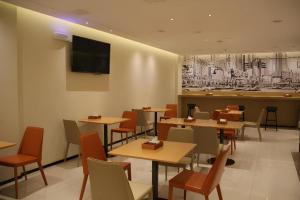 ein Restaurant mit Tischen und Stühlen und einem Fernseher an der Wand in der Unterkunft City Comfort Inn Wuhan Changfeng Avenue 3rd Hanxi Road in Wuhan