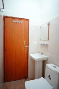 uma casa de banho com uma porta de madeira e um WC e lavatório em LVMR RIDER REST Homestay em Kulu
