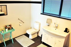 a bathroom with a white toilet and a sink at Pacific Paradise Apartment in Tutukaka +9 photos