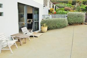 a patio with two white chairs and a table at Pacific Paradise Apartment in Tutukaka