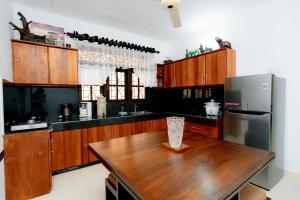 Una cocina con una mesa de madera y un refrigerador. en Brescia Villa - Your Private Escape in Matara, en Gandara West