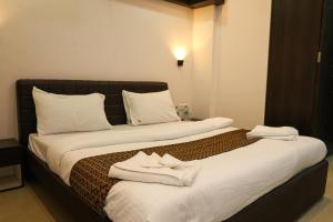 two beds in a hotel room with towels on them at Sairaah Golden Suites, Shirdi in Shirdi