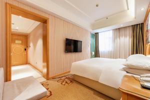 a hotel room with a bed and a television at Vienna Hotel Qinghai Xining Wanda Plaza in Xining