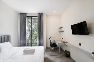 ein Hotelzimmer mit einem Bett, einem Schreibtisch und einem Fernseher in der Unterkunft Cove Legacy in Jakarta