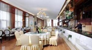 a restaurant with a table and chairs and a man standing at a counter at Vienna Hotel Henan Xinyang East Zone of Central Hospital in Pingqiao