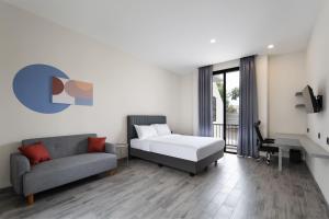 ein Schlafzimmer mit einem Bett, einer Couch und einem Schreibtisch in der Unterkunft Cove Legacy in Jakarta
