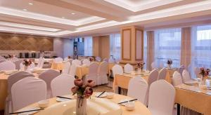 a banquet hall with white tables and white chairs at Vienna Hotel Henan Luoyang Jiudu Road Wanda in Luoyang