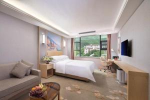a bedroom with a bed and a couch and a desk at Vienna Hotel Guangxi Hechi Jinchengjiang Baima Street in Hechi