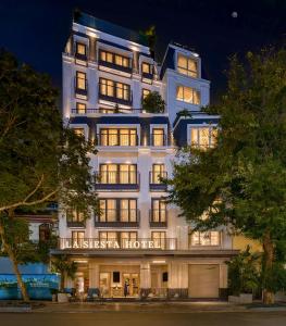 ein großes weißes Gebäude mit eingeschalteten Lichtern in der Unterkunft La Siesta Premium Lakeside in Hanoi