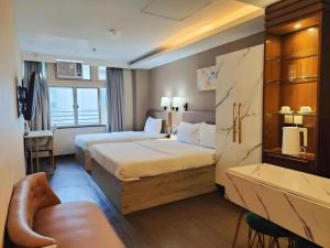a hotel room with two beds and a couch at Sunny Day Hotel in Hong Kong